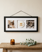 Black frame with a cat nose print and two cat photos hanging on a wall